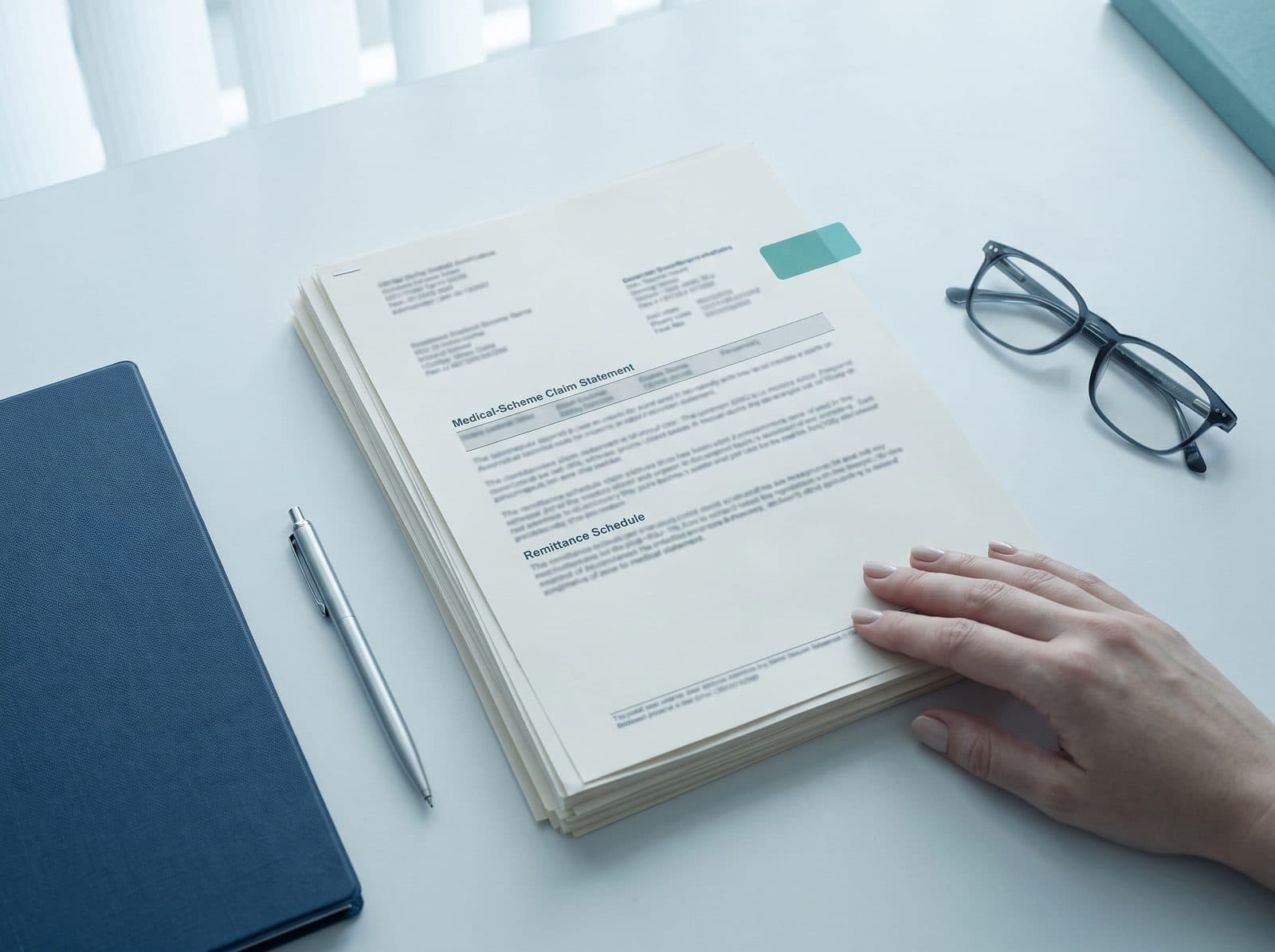 A medical scheme claim statement and remittance schedule being reviewed on a desk